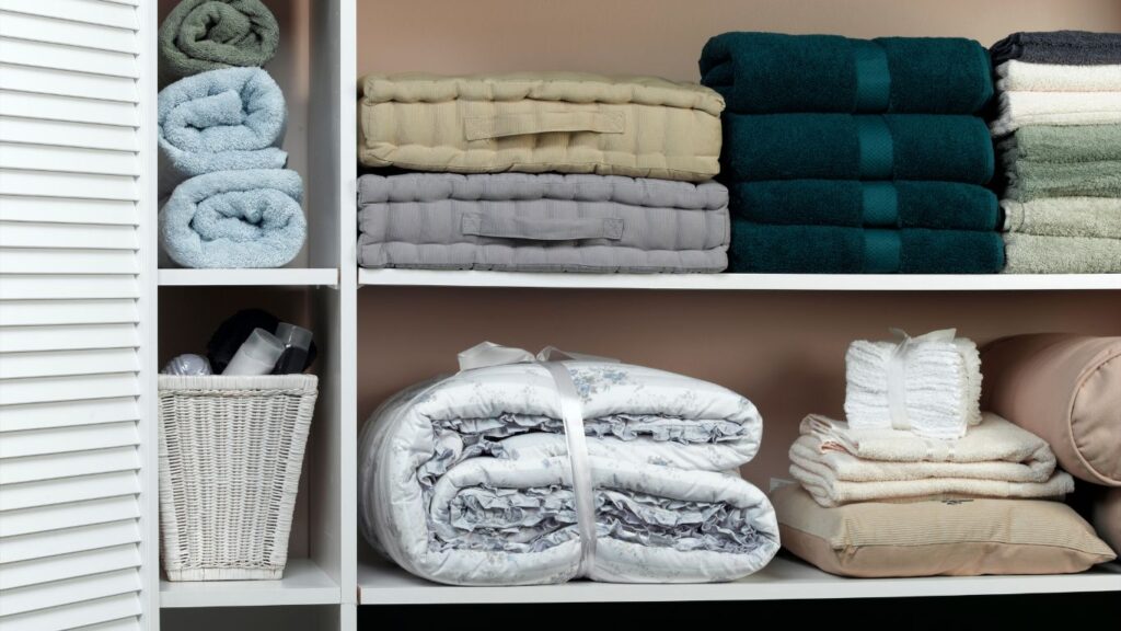 A shelf with folded blankets and towels on it.